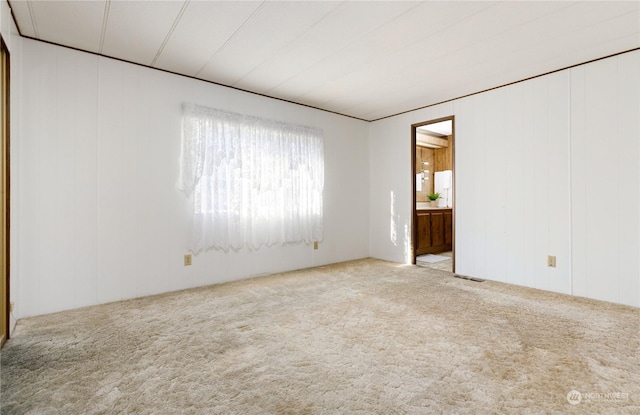 unfurnished room with light colored carpet and wooden walls