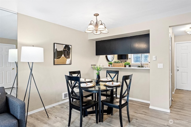 dining area with a chandelier and light hardwood / wood-style flooring