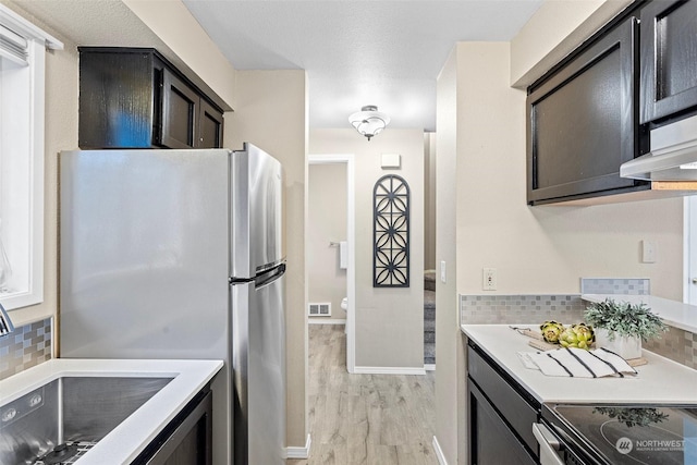 kitchen with stainless steel appliances, tasteful backsplash, sink, and light hardwood / wood-style flooring