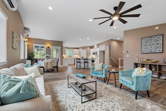 living room with lofted ceiling, a wall mounted air conditioner, and light hardwood / wood-style floors