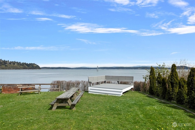 view of dock featuring a lawn and a water view