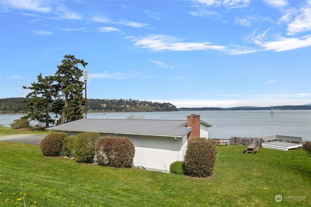 view of side of home with a water view and a yard