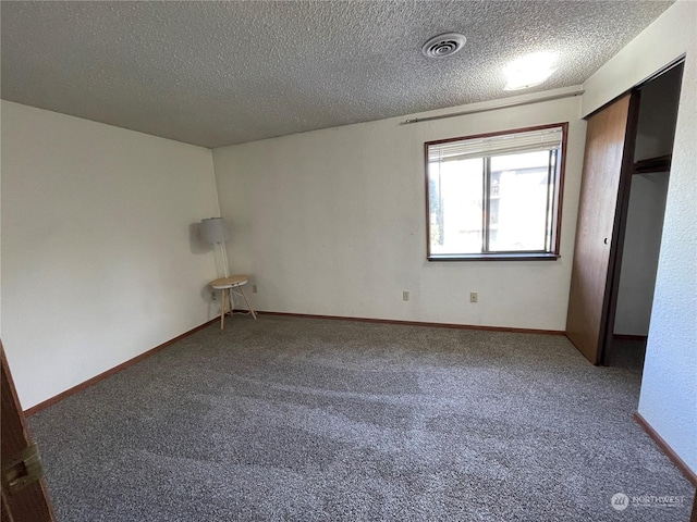 empty room with carpet floors and a textured ceiling