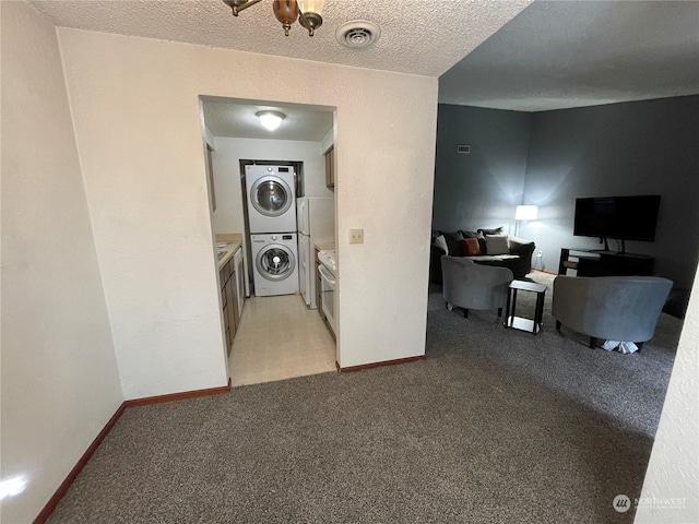 clothes washing area with light colored carpet, stacked washer and clothes dryer, and a textured ceiling