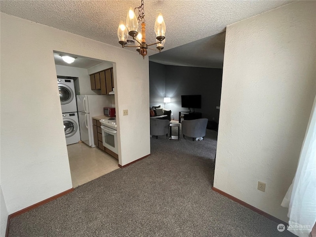 hallway featuring light carpet, a textured ceiling, an inviting chandelier, and stacked washer / dryer