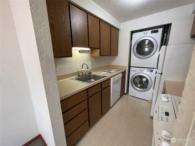 laundry area with stacked washer and clothes dryer, sink, and a textured ceiling