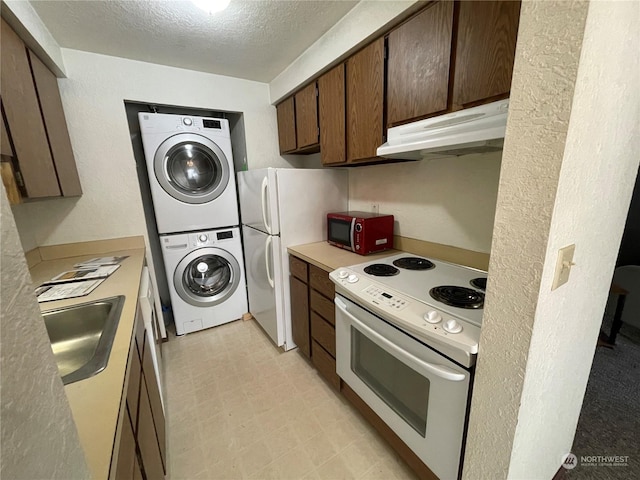 kitchen with sink, white appliances, a textured ceiling, and stacked washer / dryer