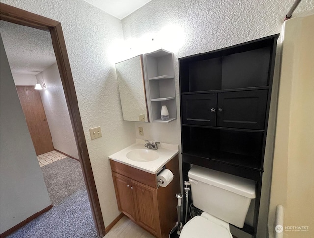 bathroom with vanity, toilet, and a textured ceiling