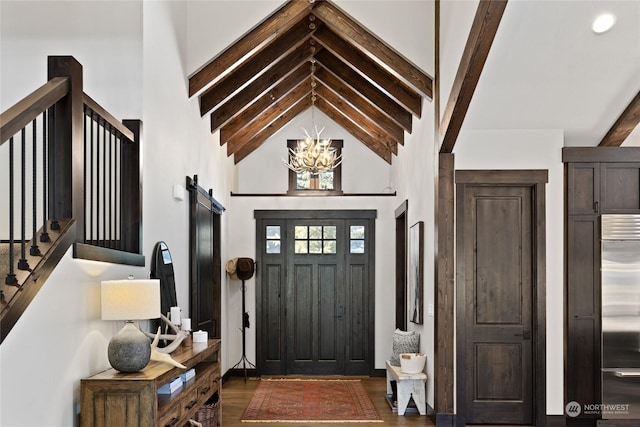 entryway with dark hardwood / wood-style flooring, a notable chandelier, high vaulted ceiling, and a barn door