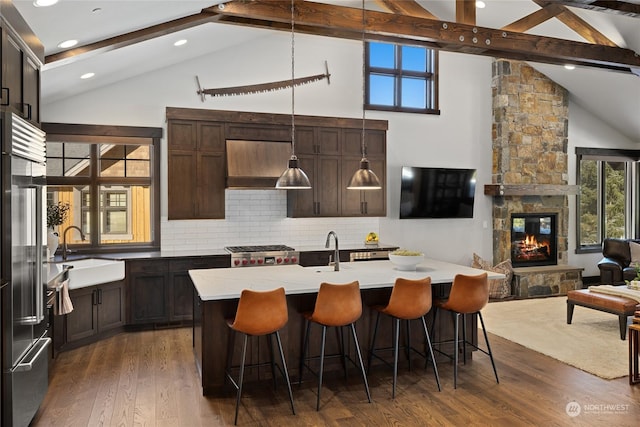 kitchen featuring a stone fireplace, pendant lighting, an island with sink, sink, and high end refrigerator