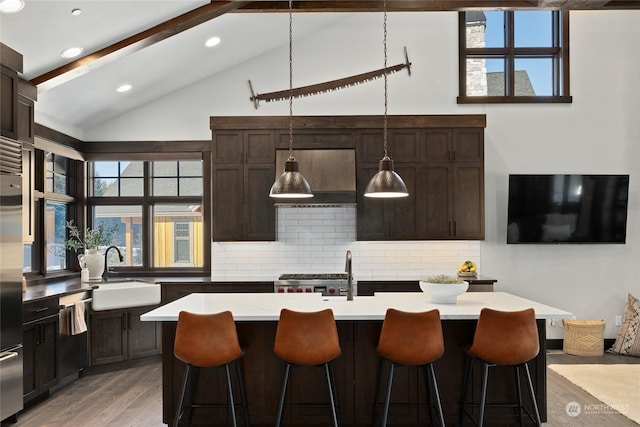 kitchen with pendant lighting, sink, an island with sink, and beamed ceiling