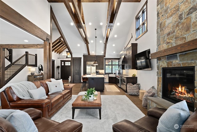 living room with light hardwood / wood-style flooring, beam ceiling, a fireplace, and high vaulted ceiling