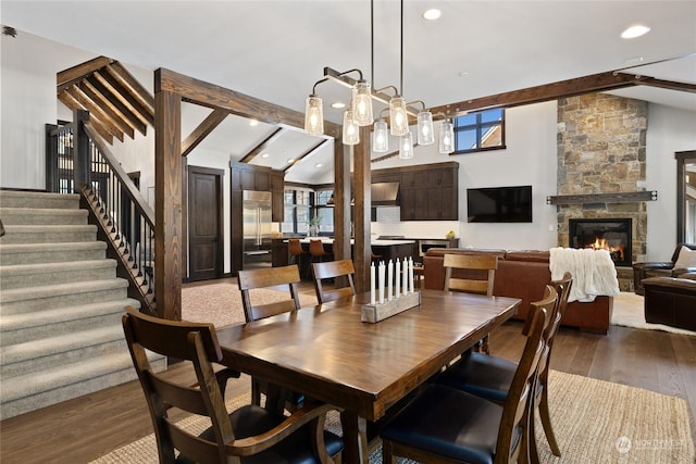 dining room featuring high vaulted ceiling, beam ceiling, hardwood / wood-style floors, and a stone fireplace