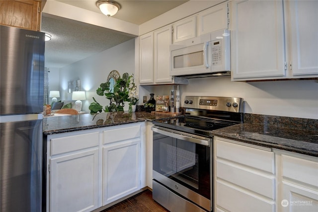 kitchen featuring appliances with stainless steel finishes, white cabinetry, dark hardwood / wood-style floors, a textured ceiling, and dark stone counters