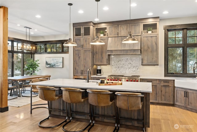 kitchen featuring decorative backsplash, a kitchen breakfast bar, a kitchen island with sink, and hanging light fixtures