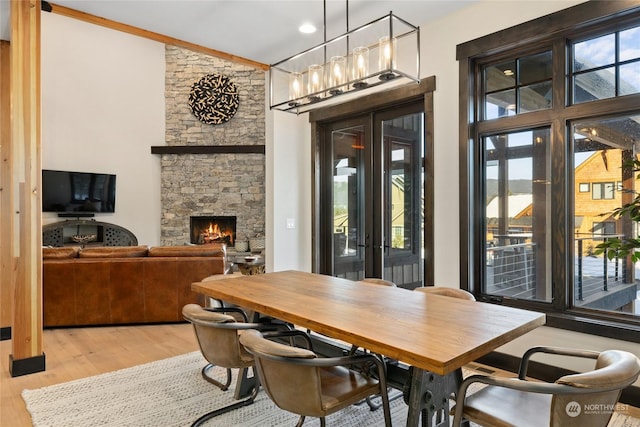 dining room with a fireplace, light hardwood / wood-style floors, and french doors