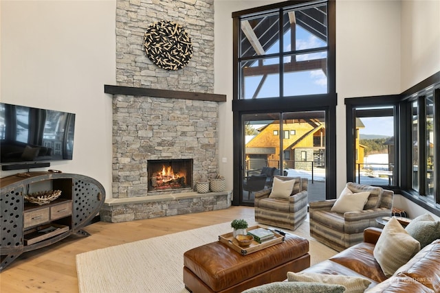 living room featuring hardwood / wood-style flooring, a high ceiling, and a fireplace