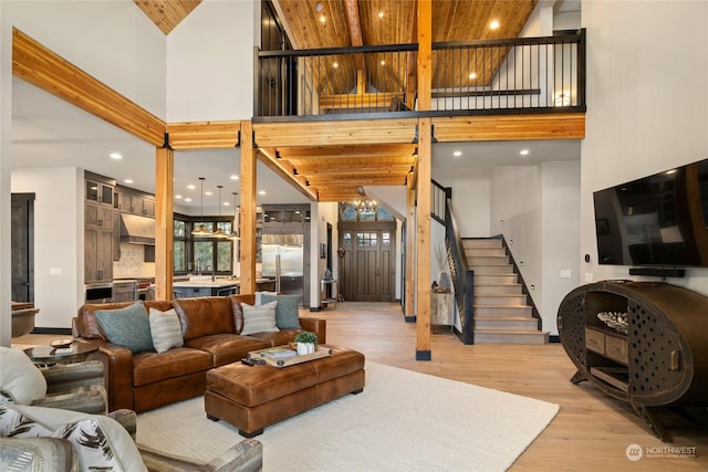 living room with wood ceiling, a towering ceiling, and light wood-type flooring