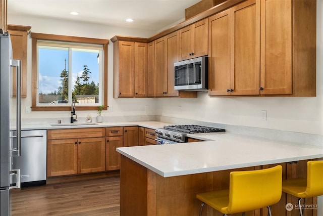 kitchen with sink, dark wood-type flooring, a kitchen breakfast bar, high end appliances, and kitchen peninsula