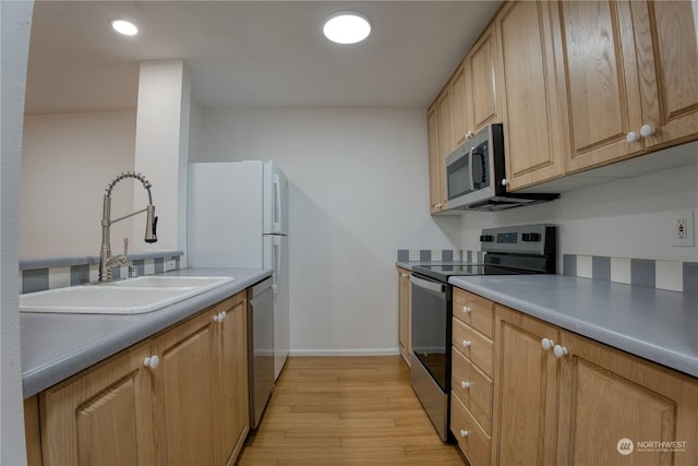 kitchen featuring stainless steel appliances, sink, light brown cabinetry, and light wood-type flooring