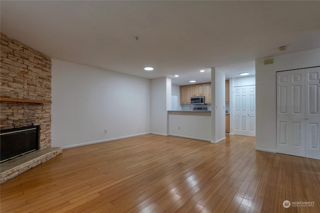 unfurnished living room with a stone fireplace and light hardwood / wood-style flooring