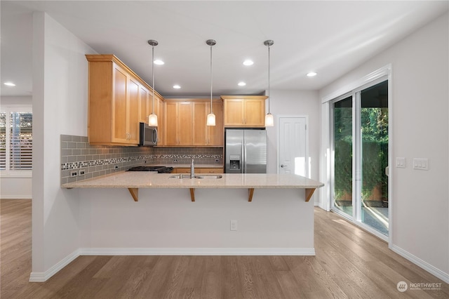 kitchen featuring sink, decorative light fixtures, light wood-type flooring, appliances with stainless steel finishes, and light stone countertops