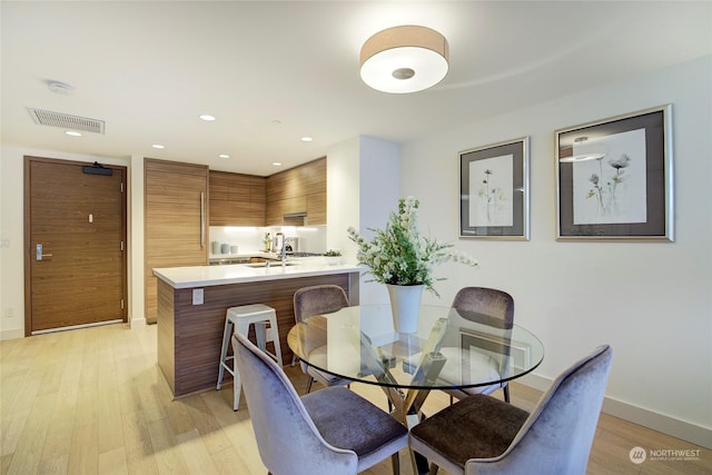 dining space with sink and light wood-type flooring