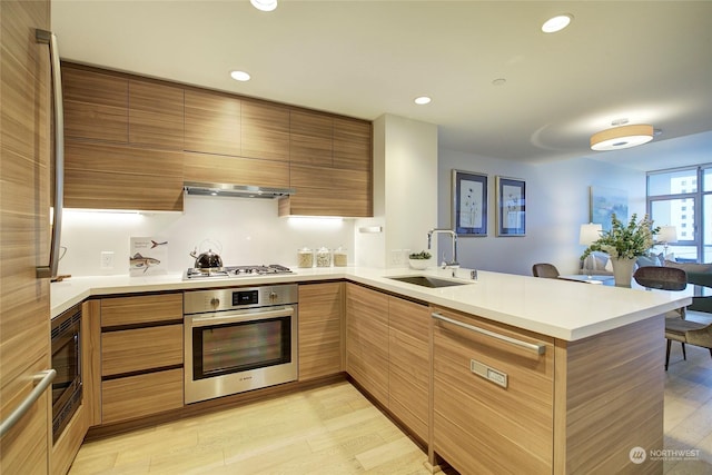 kitchen with sink, exhaust hood, light hardwood / wood-style floors, kitchen peninsula, and stainless steel appliances