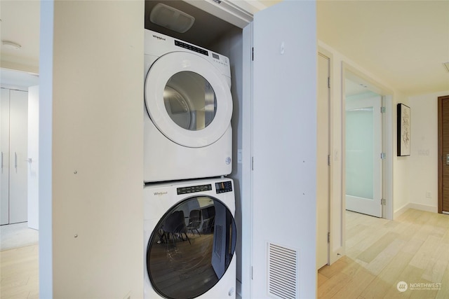 washroom featuring stacked washer / dryer and light hardwood / wood-style flooring