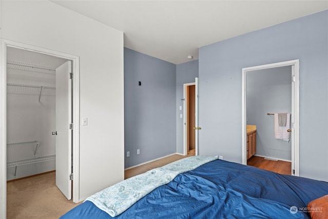 carpeted bedroom with a walk in closet, a closet, and ensuite bathroom