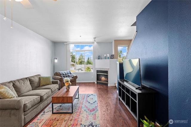 living room featuring dark hardwood / wood-style flooring, a tiled fireplace, and ceiling fan