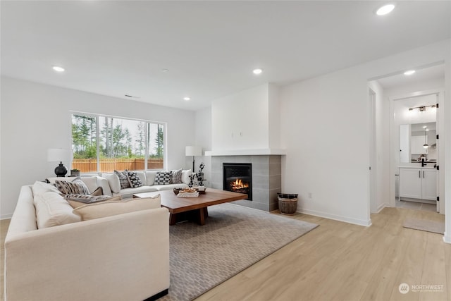 living room featuring a tiled fireplace and light hardwood / wood-style flooring