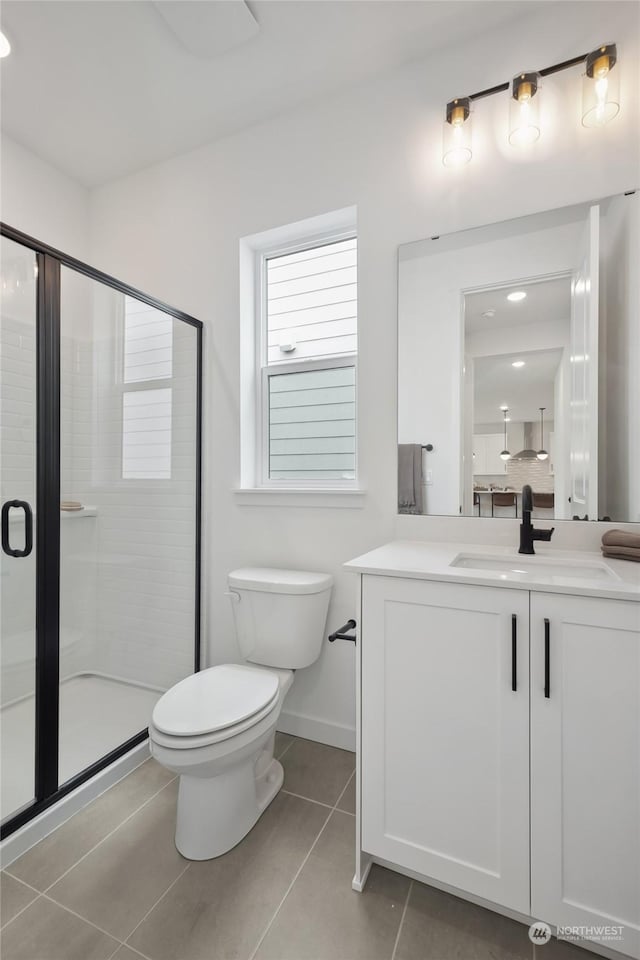 bathroom featuring toilet, vanity, a shower with door, and tile patterned flooring