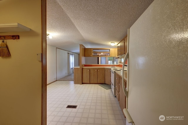 kitchen featuring white appliances, vaulted ceiling, and a textured ceiling