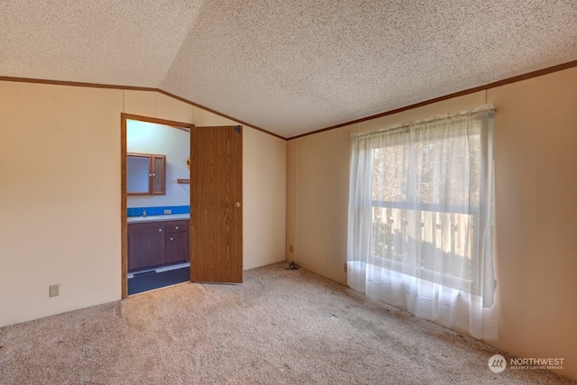 unfurnished bedroom featuring ensuite bath, carpet flooring, vaulted ceiling, and a textured ceiling