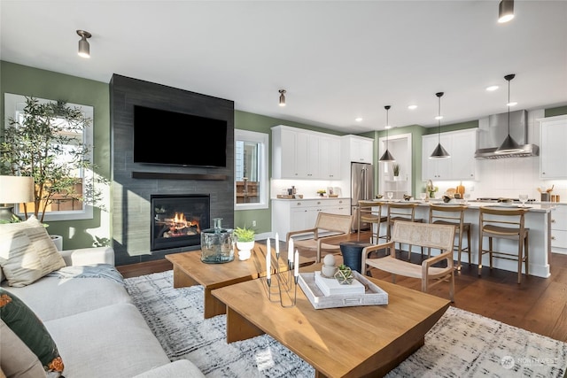 living room featuring a tiled fireplace and dark wood-type flooring