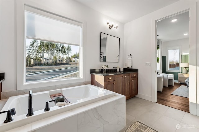 bathroom with vanity, tiled tub, and tile patterned flooring