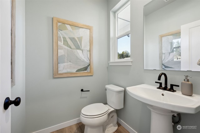 bathroom featuring a healthy amount of sunlight, toilet, sink, and wood-type flooring