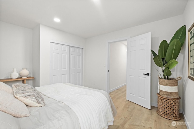 bedroom with light hardwood / wood-style floors and a closet