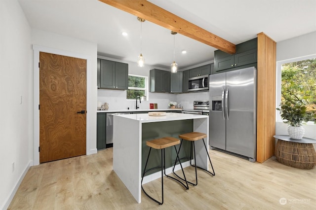 kitchen featuring sink, appliances with stainless steel finishes, a kitchen island, a wealth of natural light, and decorative backsplash