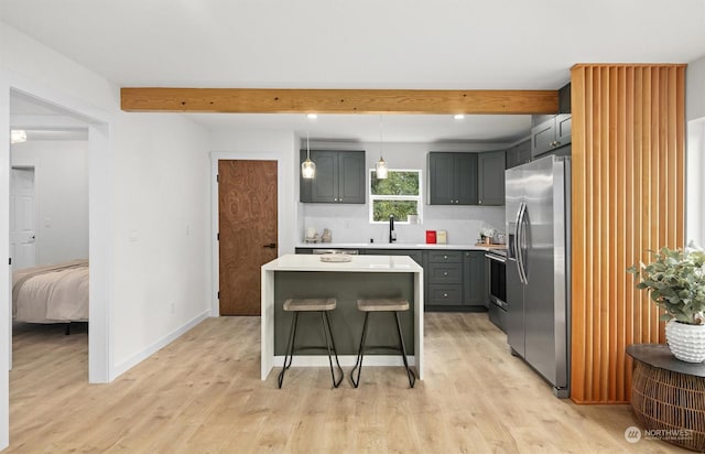 kitchen featuring gray cabinets, appliances with stainless steel finishes, decorative light fixtures, a kitchen bar, and a center island