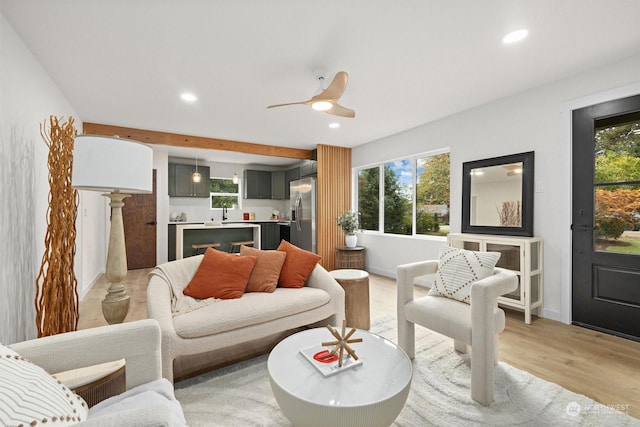 living room featuring ceiling fan, sink, and light wood-type flooring