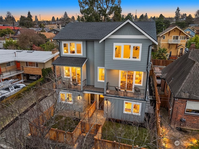 back house at dusk featuring a balcony