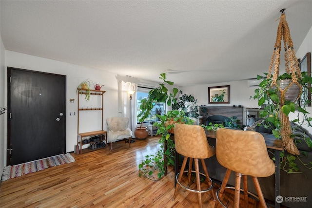 dining area with bar, hardwood / wood-style floors, and a textured ceiling