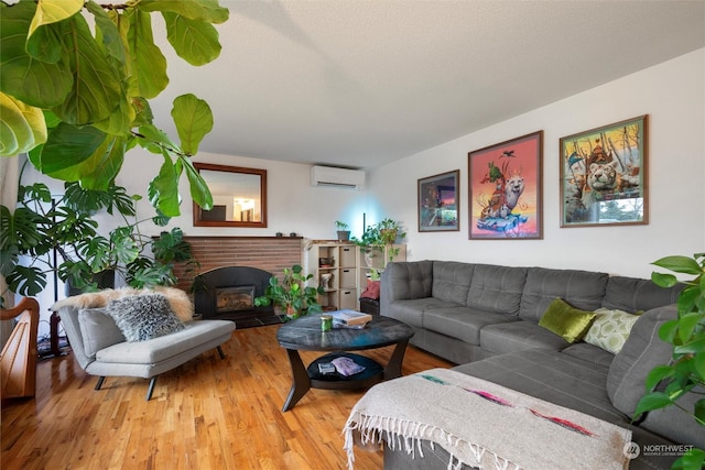 living room featuring a fireplace, light hardwood / wood-style floors, and a wall unit AC