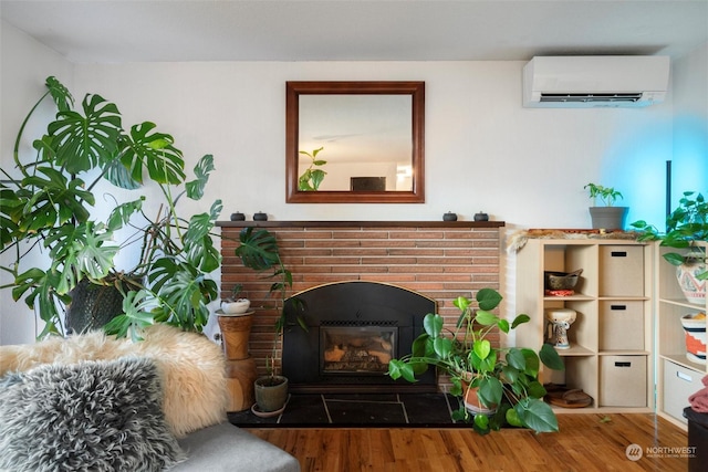 living room with a brick fireplace, wood-type flooring, and a wall mounted AC