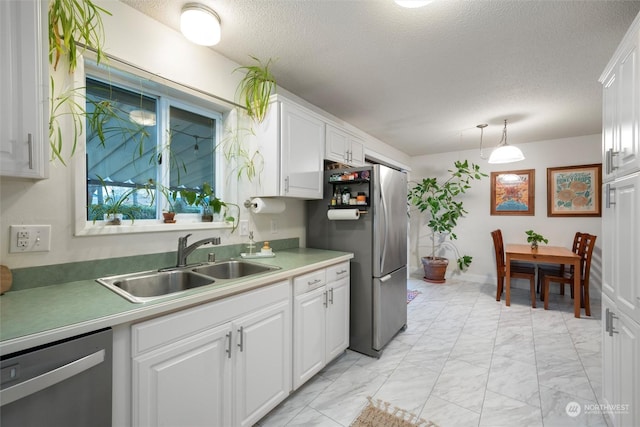 kitchen with white cabinetry, sink, hanging light fixtures, stainless steel appliances, and a textured ceiling