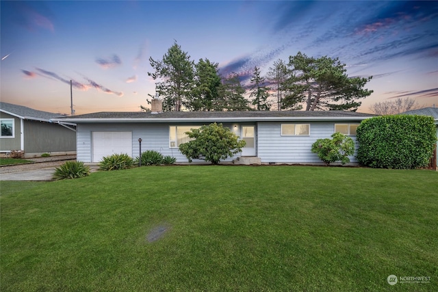 ranch-style house featuring a garage and a lawn