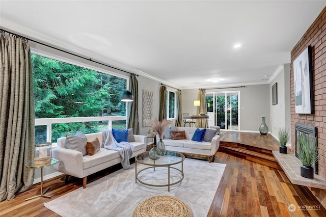 living room featuring a brick fireplace, ornamental molding, and hardwood / wood-style floors