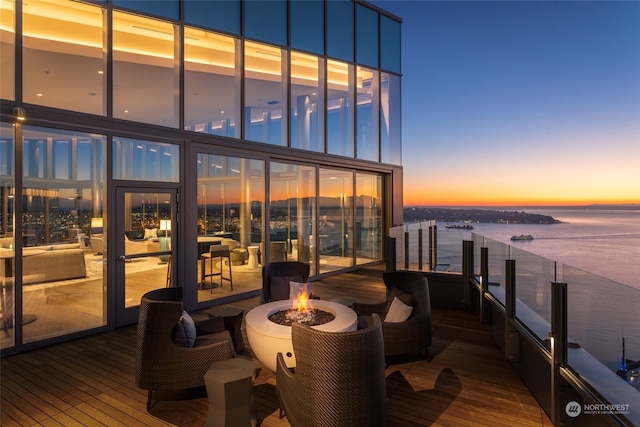 deck at dusk featuring an outdoor fire pit and a water view